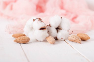 almonds and cotton with rose textile on whte wooden table. selec