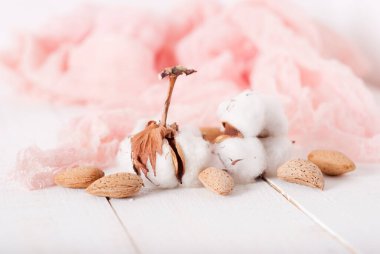 almonds and cotton with rose textile on whte wooden table. selec