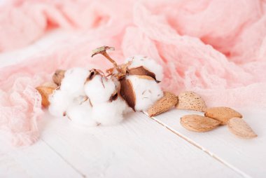 almonds and cotton with rose textile on whte wooden table. selec