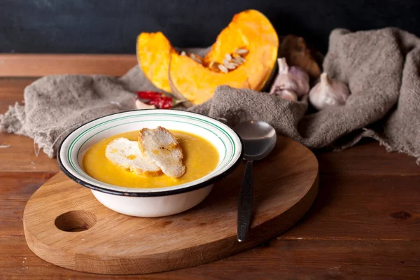 hot spice pumpkin soup with garlic, chili pepper, ginger on wooden table