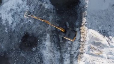 Orange excavator extracting ore in a coal quarry. Top view from the copter.4K