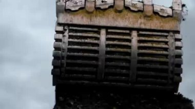 The big ladle scoops up ore with soil and loads into the dump truck, ore spills out of the dumper. 4K