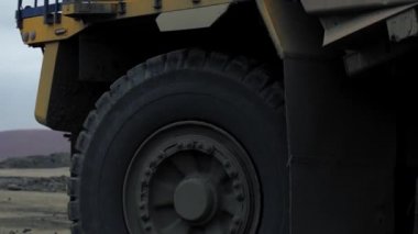 A huge dump truck transports ore and soil. The close-up shot from the wheel to the body of the dump truck. A quarry, mining of metals. 4K