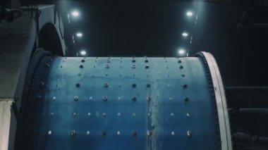 An industrial drum for grinding ore is spinning on a production line. Bottom view of the drum. Shooting inside the factory. 4