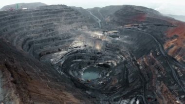 The camera is flying over the ore mines. Orange heavy machinery is working at the mine. Beautiful view. Panorama. 4K