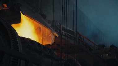 Bright flame in a metallurgical furnace. Close-up of the furnace. Sparks splatter. Many holding cables on the right. Metallurgical production process. 4K
