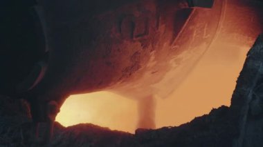 Pouring bright hot liquid steel or metal from ladle in a blast furnace foundry metallurgical factory. Steel mill iron smelting process with bright sparks and smoke.4K