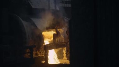 Molten metal flows from the furnace into the ladle. Sparks splatter from the ladle. Metallurgical production process. Ironworks. 4K