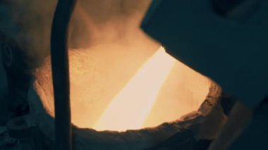 A strong stream of molten metal flows into the melting pot. Metalworking process. Metallurgy. Close-up. 4K