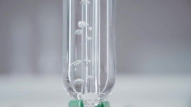 Bright laboratory. Glass flask. Water boils in the flask. Chemical reactions. Vertical panorama. Camera moves from bottom to top. 4K