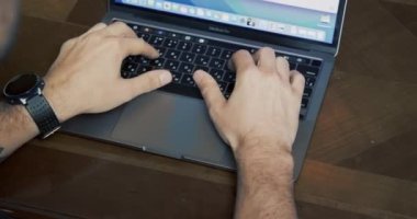 Saati ve dövmesi olan bir adam MacBook Pro 'da çalışıyor. Elleri yakın çekim. Meşgul biri. Bir işadamı. 4K