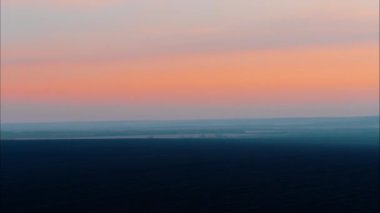 Siyah bir vadide pembe gün batımı. Pastel gökyüzü tonu, güzel gökyüzü. Yerin üstündeki helikopterden panorama. Gökyüzünde sis var. 4K.