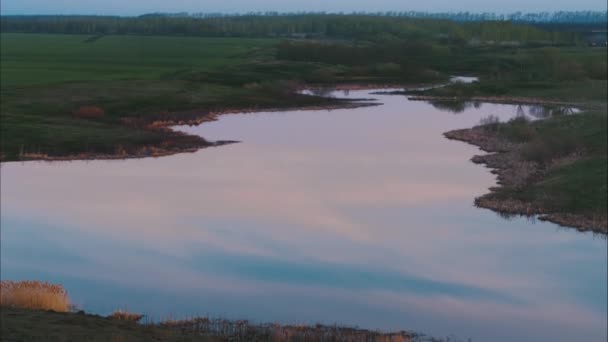 日落时分 在一条美丽的蜿蜒流过的河流之间的绿色草地上飞行 天空在平静的河里反射 顶部视图 — 图库视频影像