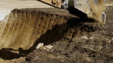 Toprak temizleyen bir kazıcı kovasına yakın çekim. Taş ocağında çalışma süreci. Sarı renk şeması. Ağır endüstri. 4K