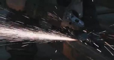 Güvenlik kaskı takan usta bir el değirmeniyle çalışıyor. Uçan kıvılcımlar. Deburding metal. El işçiliği. Çaktırmadan ateş etmek. Marangoz. 4