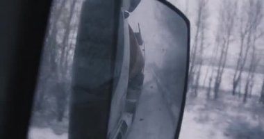 Tanker kamyonundaki ayna görüntüsü. Kış yolu. Çıplak ağaçlar. Bir kamyoncunun işi. 4K