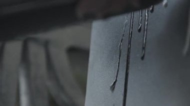 Close-up of graffiti drawing on a wall. Street artist paints with spray can of black paint. Artist's hand with tattoos and painted black nails. Street art. 4K