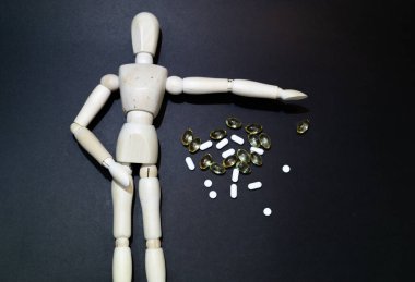 The dangers of Drug overdose concept, symbolized by an anonymous wooden mannequin. black background