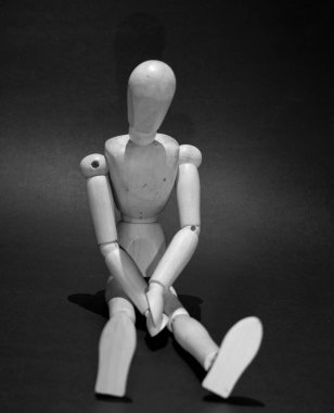 sad wooden mannequin on a black background
