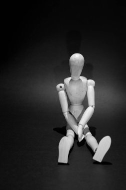 sad wooden mannequin on a black background