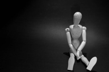 sad wooden mannequin on a black background