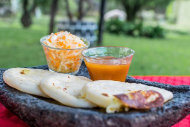 typical Salvadoran dish, cheese pupusas with cabbage and tomato sauce. rice and corn pupusas stuffed with cheese, beans or other ingredients
