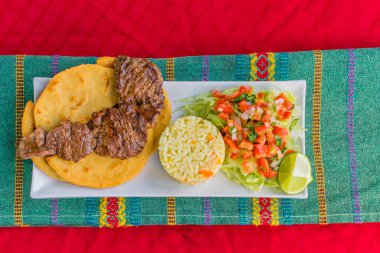 typical Salvadoran dish, roast beef, rice, chirmol and pupusas