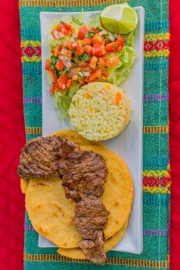 typical Salvadoran dish, roast beef, rice, chirmol and pupusas