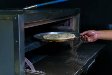 putting an artisanal pizza in the oven.