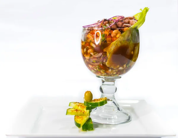 shrimp cocktail garnished with cucumbers black background white plate