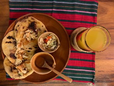 typical Salvadoran dish, cheese pupusas with cabbage and tomato sauce. rice and corn pupusas stuffed with cheese, beans or other ingredients. Orange juice