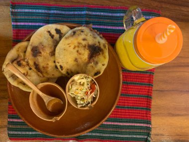 typical Salvadoran dish, cheese pupusas with cabbage and tomato sauce. rice and corn pupusas stuffed with cheese, beans or other ingredients. Orange juice