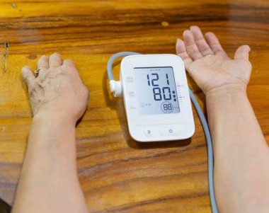 arms of an elderly lady measuring blood pressure