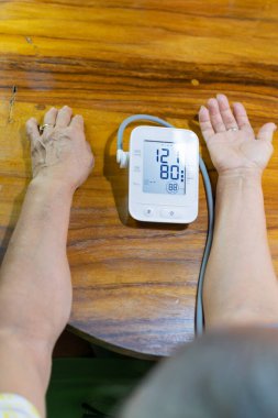 arms of an elderly lady measuring blood pressure