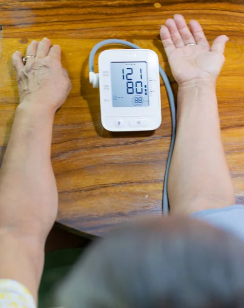 arms of an elderly lady measuring blood pressure