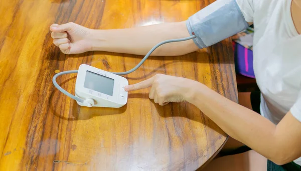 young woman measuring blood pressure and heart rate at home