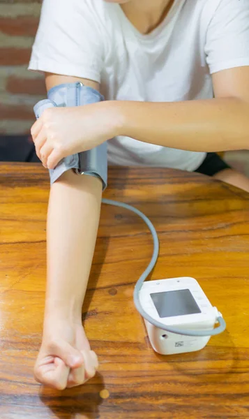 young woman measuring blood pressure and heart rate at home