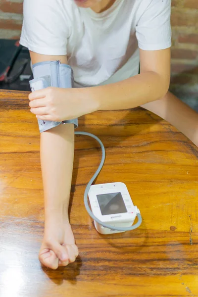 young woman measuring blood pressure and heart rate at home