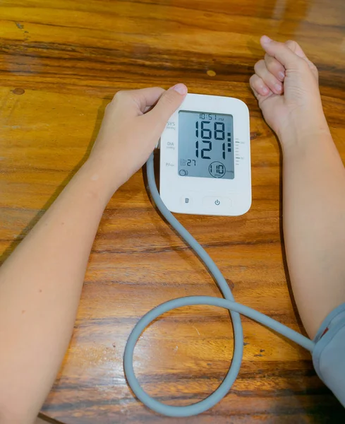 arms of young woman taking her blood pressure with abnormal results