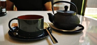 ceramic cup of tea with kettle on table