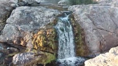 a river with a waterfall among beautiful rocks