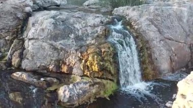 a small waterfall on the river surrounded by beautiful rocks