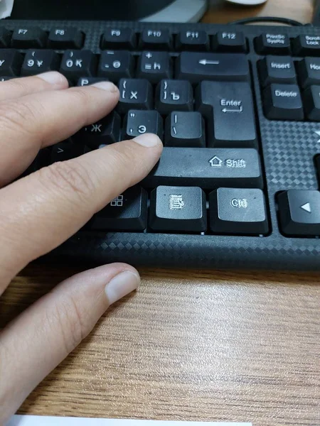 black keyboard with a hand on the desktop in the office