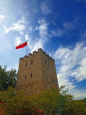 Tower of castle Tropsztyn polish flag waving on top. Summer august 2022