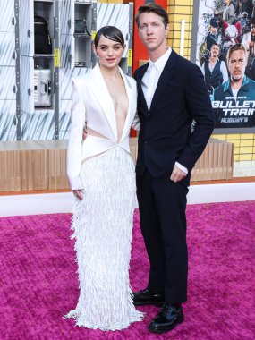 Amerikalı aktris Joey King bir Cong Tri elbisesi, Azalea Wang ayakkabıları, Shaun Leane kolyesi, Hirotaka kulaklık, ve Mara Paris yüzükleri ve erkek arkadaşı / yönetmeni Steven Piet 1 Ağustos 2022 'de Sony filmi Kurşun Treni' nin prömiyerine geldi.