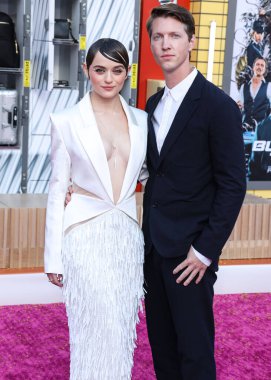 Amerikalı aktris Joey King bir Cong Tri elbisesi, Azalea Wang ayakkabıları, Shaun Leane kolyesi, Hirotaka kulaklık, ve Mara Paris yüzükleri ve erkek arkadaşı / yönetmeni Steven Piet 1 Ağustos 2022 'de Sony filmi Kurşun Treni' nin prömiyerine geldi.