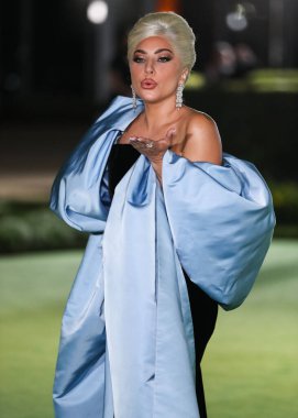 Şarkıcı Lady Gaga (Stefani Joanne Angelina Germanotta) özel bir Schiaparelli elbisesi ve Chopard mücevheri giyerek 25 Eylül 2021 'de Los Ang' daki Akademi Film Müzesi 'nin açılışındaki Akademi Müzesi' ne gelir.