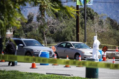 Tıbbi personel 26 Mart 2020 'de Pacoima, Los Angeles, Kaliforniya, ABD' deki Hansen Baraj Parkı 'ndaki Coronavirus COVID-19 test merkezindeki araçlarla ilgileniyor..
