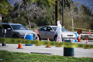 Tıbbi personel 26 Mart 2020 'de Pacoima, Los Angeles, Kaliforniya, ABD' deki Hansen Baraj Parkı 'ndaki Coronavirus COVID-19 test merkezindeki araçlarla ilgileniyor..