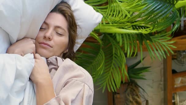 Vídeo vertical de una mujer endereza la manta, sonríe mientras duerme y duerme dulcemente. — Vídeos de Stock